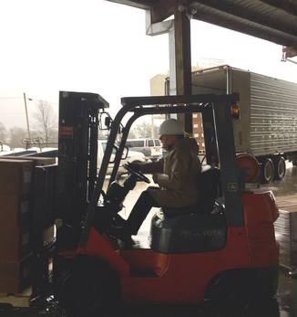 Director Bill Lincoln jockeys the forklift as the RCD receives delivery of 100,000 conifer seedlings in the downpour of February 17, 2017